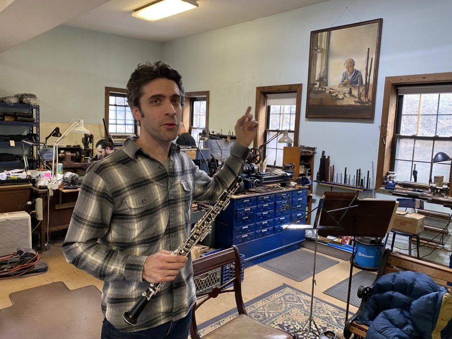 Alex Laubin holding one of his companys famed oboes and pointing to the portrait of his grandfather who started the business in 1931. 