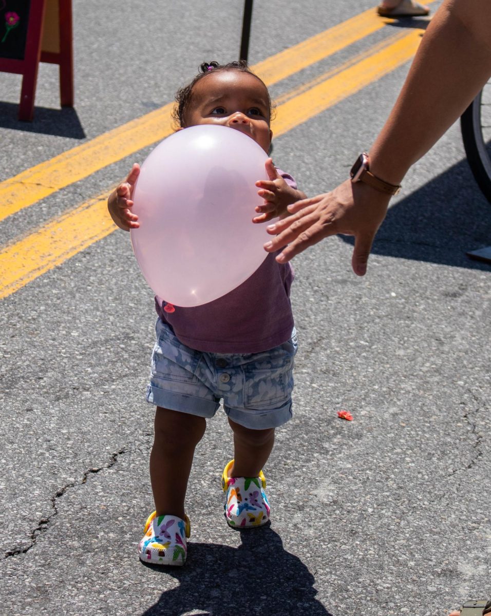 A young visitor to the market has a grip on balloon given away by Friends of Peekskill Dog Park. 