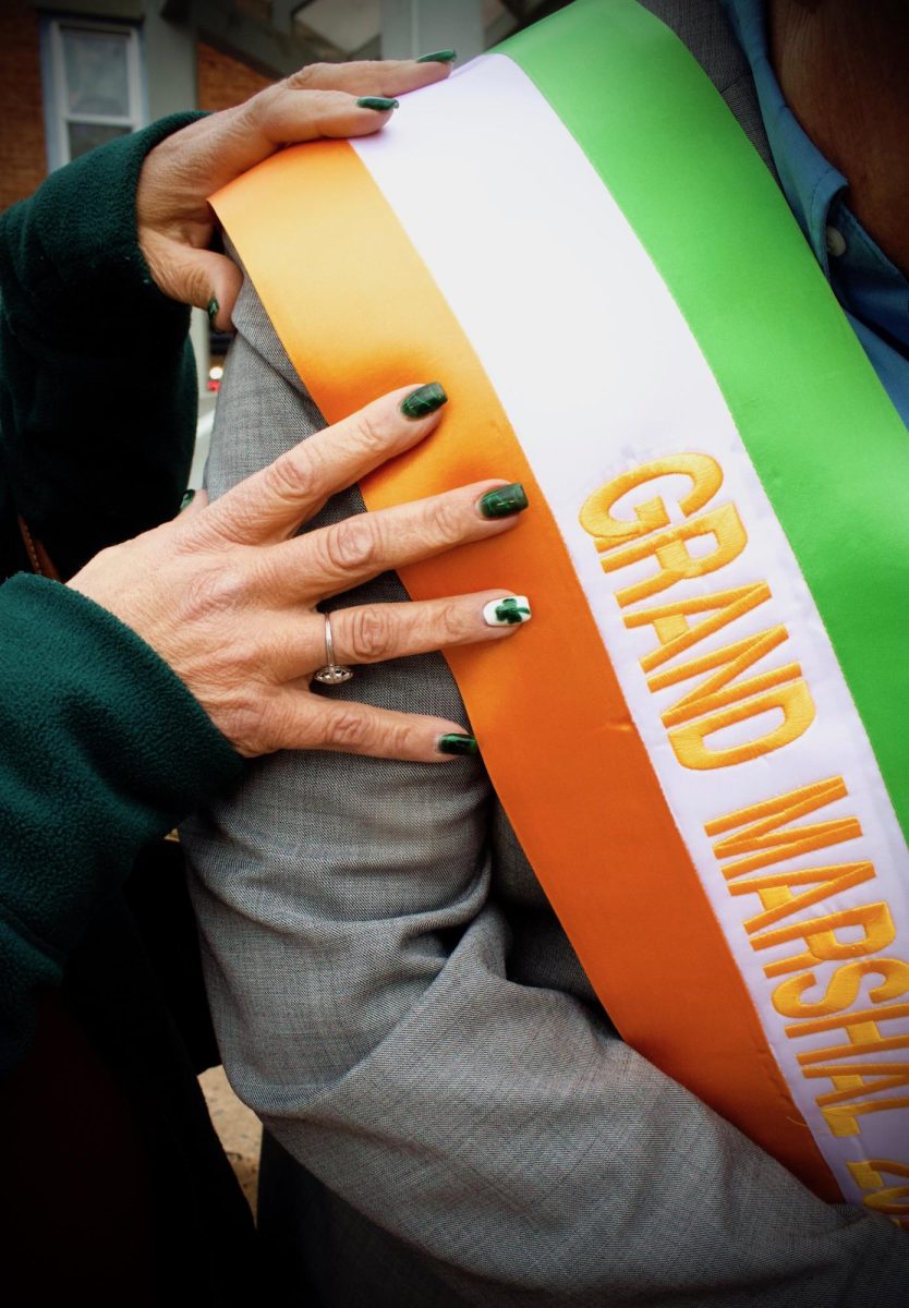 Oros' wife Marianne proudly adjusts his sash with festive nails.