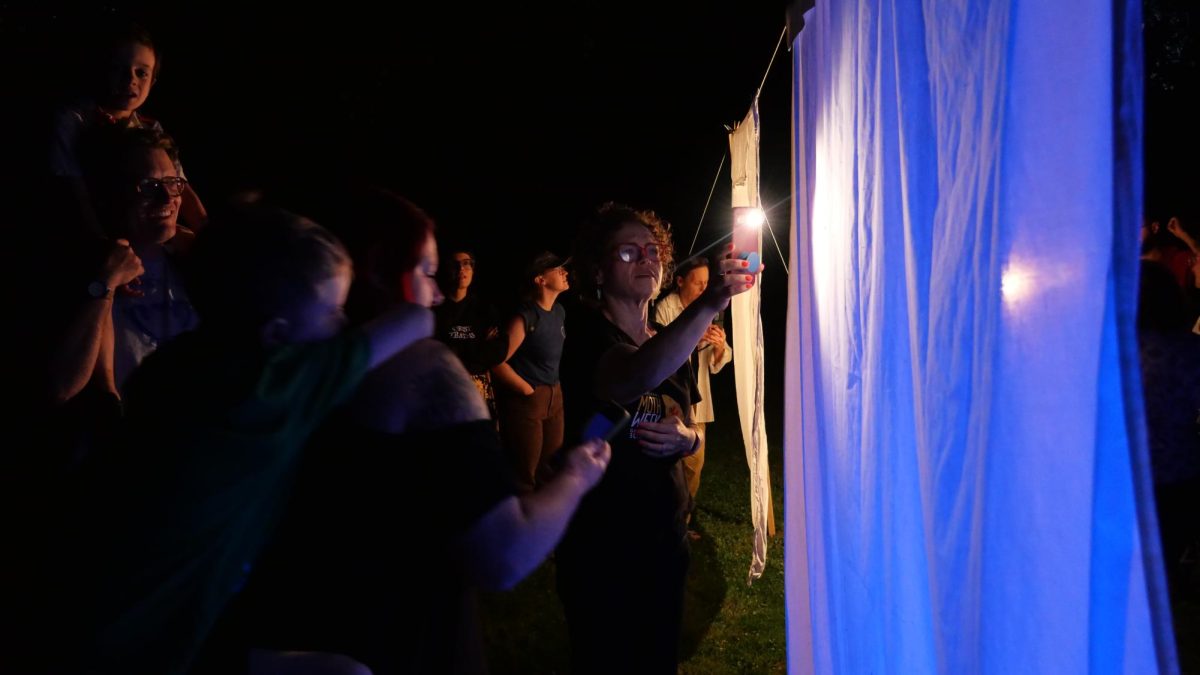 Courtney Williams holds up a light to help attendees observe and identify different moth species, guiding them through the nighttime discovery at Peekskill’s first annual Mothapalooza. (Mya Guardino)