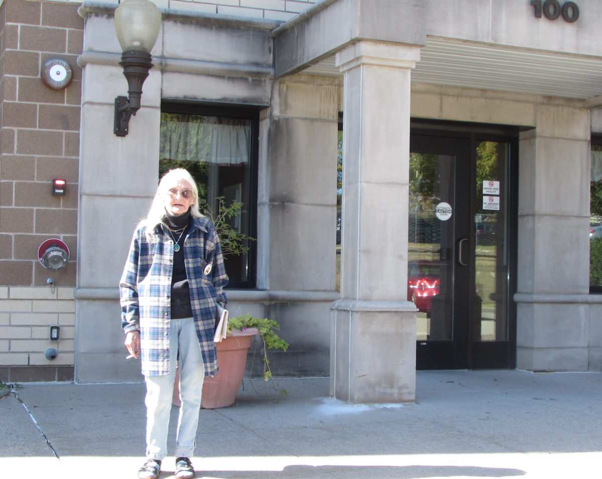 River Pointe resident Mary Cohen, seen standing in front of the building, is worried what the future may hold for tenants who can't afford the recent rent hikes.